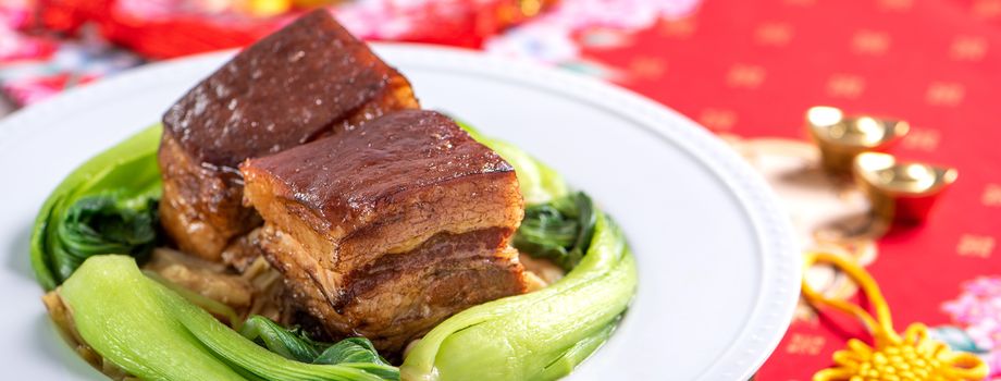 Dong Po Rou (Dongpo pork meat) in a beautiful blue plate with green broccoli vegetable, traditional festive food for Chinese new year cuisine meal, close up.