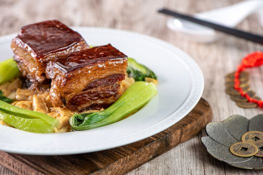 Dong Po Rou (Dongpo pork meat) in a beautiful blue plate with green broccoli vegetable, traditional festive food for Chinese new year cuisine meal, close up.