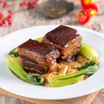 Dong Po Rou (Dongpo pork meat) in a beautiful blue plate with green broccoli vegetable, traditional festive food for Chinese new year cuisine meal, close up.