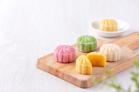 Colorful snow skin moon cake, sweet snowy mooncake, traditional savory dessert for Mid-Autumn Festival on bright wooden background, close up, lifestyle.