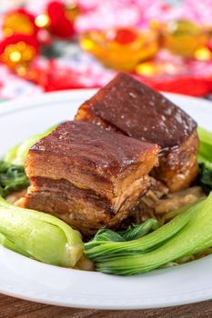 Dong Po Rou (Dongpo pork meat) in a beautiful blue plate with green broccoli vegetable, traditional festive food for Chinese new year cuisine meal, close up.