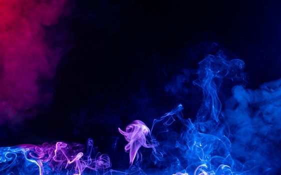 Conceptual image of multi-colored smoke isolated on dark black background, Halloween design element.