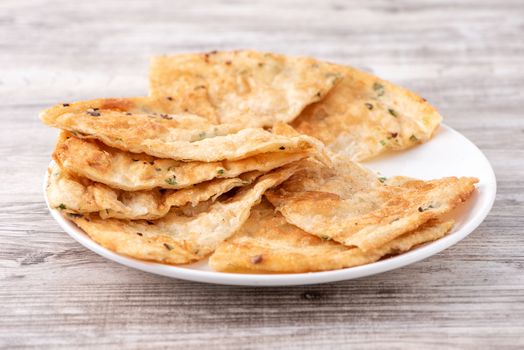 Taiwanese food - delicious flaky scallion pie pancakes on bright wooden table background, traditional snack in Taiwan, close up.