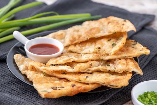 Taiwanese food - delicious flaky scallion pie pancakes on bright wooden table background, traditional snack in Taiwan, close up.