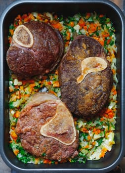 beef ossobuco meat on tray with crushed vegetables