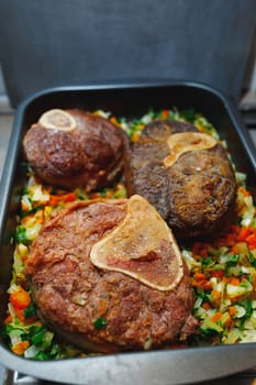 beef ossobuco meat on tray with crushed vegetables