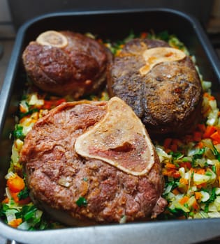 beef ossobuco meat on tray with crushed vegetables