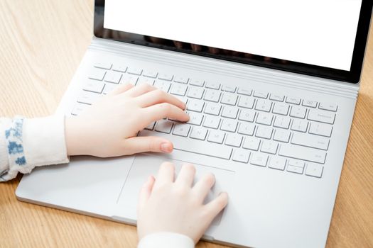 A young female child uses a computer in remote learning for her school work