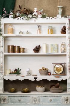 Stylish antique decor with pine cones. White cabinet with antiques on the shelves