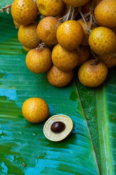 A bunch of longan branches on a background of green banana leaf. Vitamins, fruits, healthy foods.