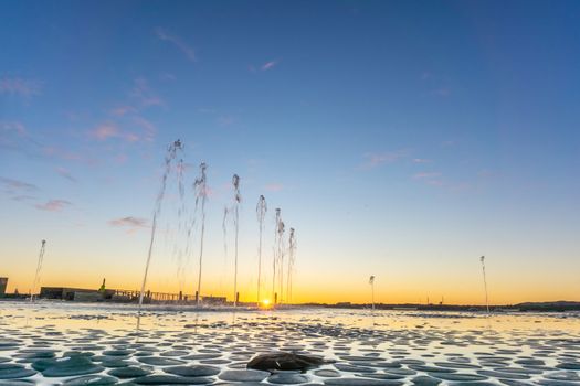 Water feature with spraying water on Tauranga Strand waterfront at sunrise with clear blue sky, New Zealand