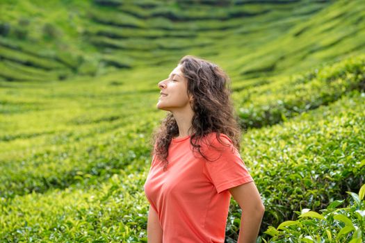 Beautiful brunette girl posing in the middle of the tea valley between green tea bushes