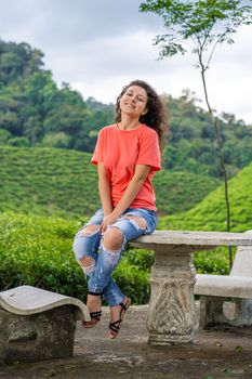 Beautiful brunette girl posing in the middle of the tea valley between green tea bushes