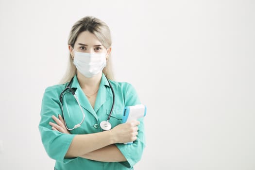 Female doctor or nurse at hospital holds pyrometer in hand. Safety measures against the coronavirus. Prevention Covid-19 healthcare concept. Stethoscope over the neck.