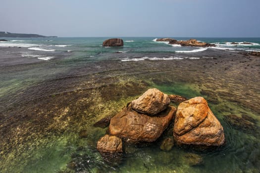 Huge rocks in clear sea near shore, with horizon in distance. Galle, Sri Lanka