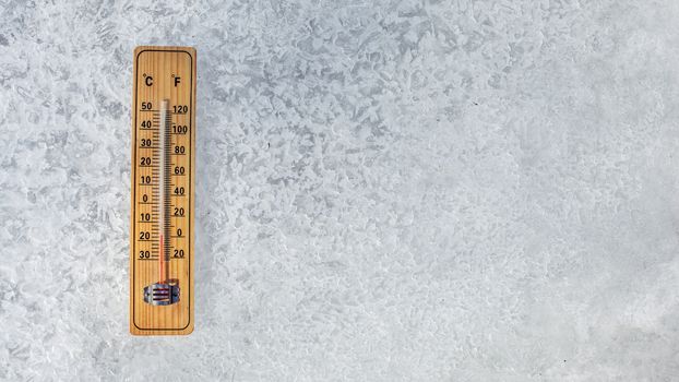 Top view on thermometer laying on layer of ice, showing temperature as low as -20 degrees Celsius. Concept illustrating extreme cold freezing weather in winter.