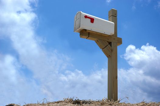 A mailbox mounted on wood stand in clear blue sky background