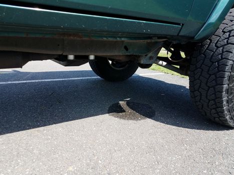 liquid puddle from leak or drip under green car or vehicle