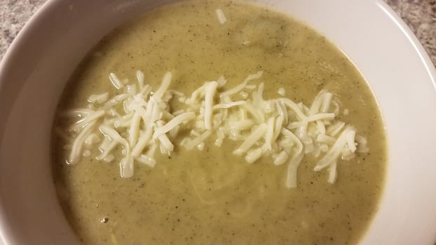 bowl of green zucchini soup with mozzarella cheese