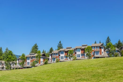 Row of new townhouses with recreation area across the road and parked car on the road