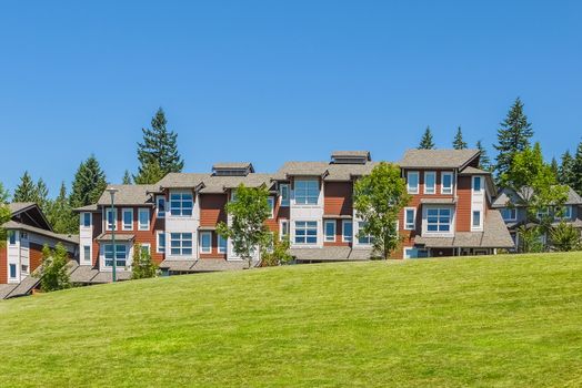 Row of new townhouses with recreation area across the road and parked car on the road