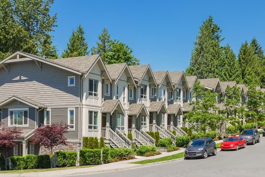 Street of new townhouses with cars parked on the road