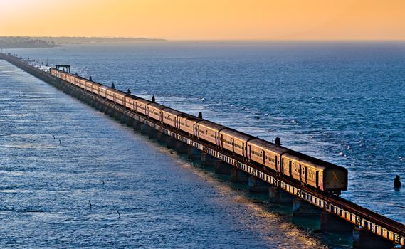 Evening golden sunlight reflects on the sides of Chennai bound Boat Mail express over Pamban bridge.