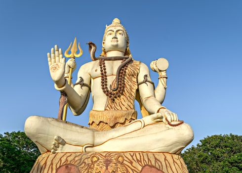 82 feet tall statue of Hindu god , Lord Shiva, with clear blue sky background at Nageshwar temple, Dwarka, Gujrat, India.