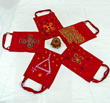 Bright red Colored cotton bags with hand painted symbols & diya arranged in pattern. Can be used as background.