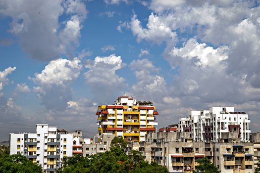 Nice, beautiful clouds on the background of tall yellow and red highrise building in Pune, India.