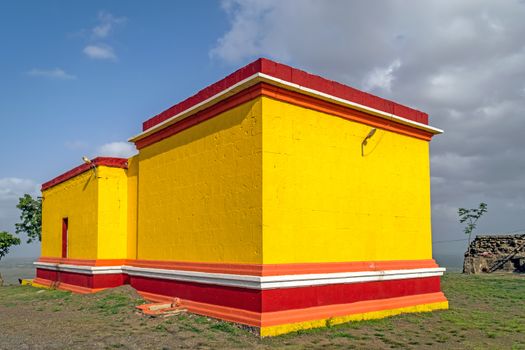 Bright yellow and red painted Dhavaleshwar temple with nice blue sky , situated on Dhavalgad fort, Purandar near Pune,Maharashtra, India.