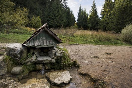 mineral spring covered with small wooden roof during summer, Liptov, Slovakia