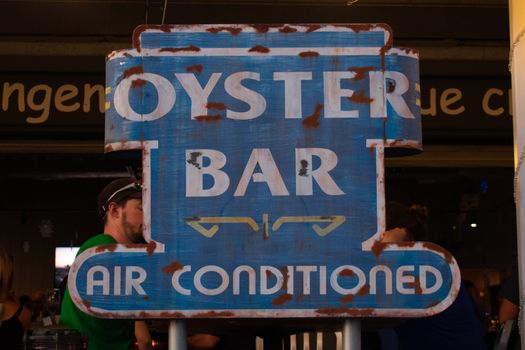 An Old Rusty Oyster Bar Sign That Also Says Air Conditioned in a Restaurant