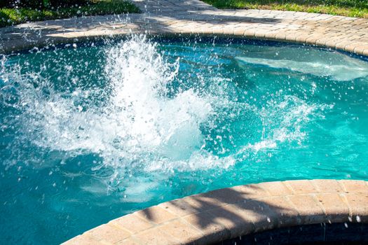 A Large Splash of Water in a Swimming Pool Caused By a Boy Jumping Into the Water