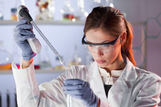 Life scientists researching in laboratory. Focused female life science professional pipetting solution into the glass cuvette. Lens focus on researcher's eyes. Healthcare and biotechnology concept.