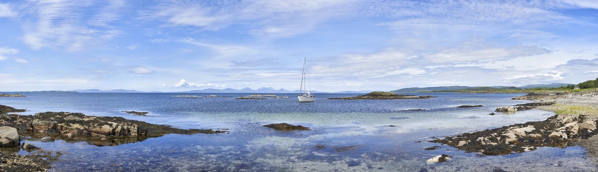 Panoramic view of sailing boat moored in clear water at Ronachan Point, Kintyre off the West coast of Scotland