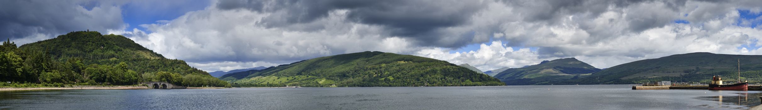 Panoramic view from Inveraray of Loch Fyne with boat moored in harbour and hills in background