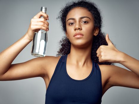 Sportive woman holding in hand a bottle with water healthy food positive hand gesture workout motivation