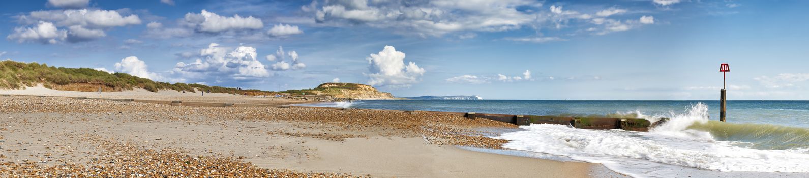 Panoramic view of Hengistbury Head beach, Dorset with groyne in the foreground and Isle of Wright Needles in background