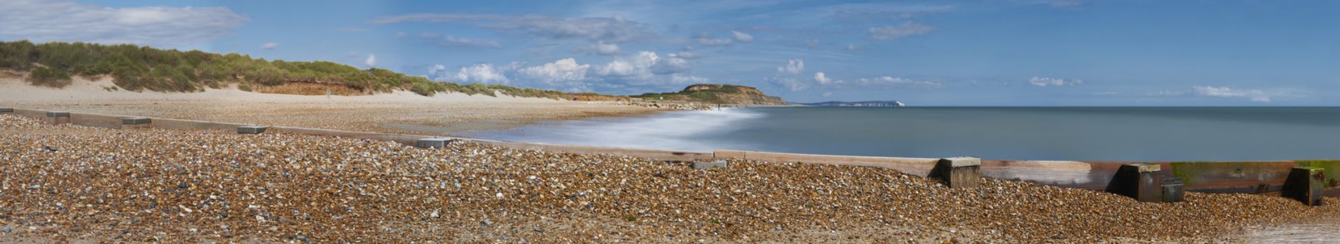 Panoramic view of Hengistbury Head beach, Dorset with groyne in the foreground and Isle of Wright Needles in background