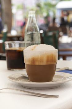 Close-up of cup of cappuccino on table in Mediterranean cafe with blurred background