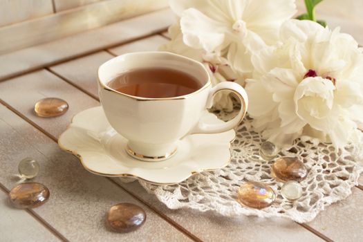 Still life concept with a white cup and a bunch of peonies