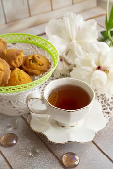 Afternoon tea served with a cupcakes, shabby table with white peony, vertical image