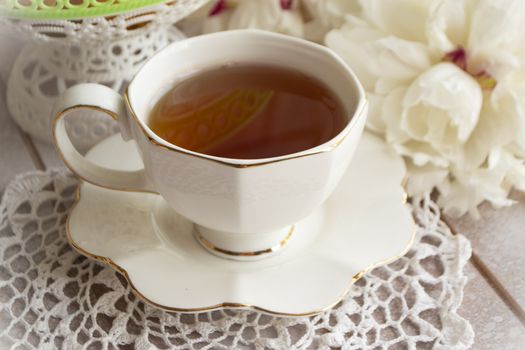 Tea on a summer day. Still life with a cup of tea, white bouquet of peonies on a white lace tablecloth