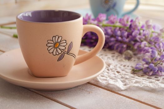 cup with coffee and pink purple lupine flowers. Lupine with long stem. Aroma and good morning concept. Lifestyle