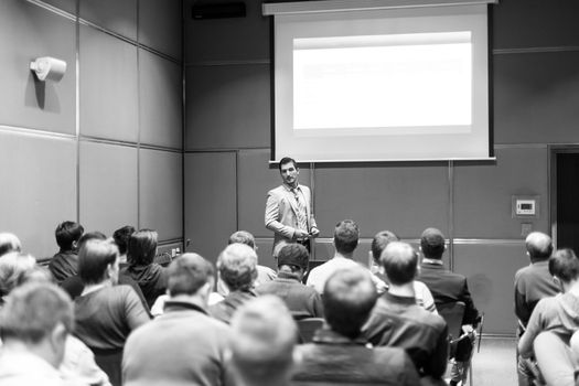 Speaker giving a talk in conference hall at business meeting event. Rear view of unrecognizable people in audience at the conference hall. Business and entrepreneurship concept.