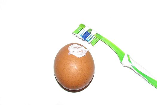                        the egg smeared toothpaste with toothbrush concept of strengthening and protecting the structure of the shell on white background        