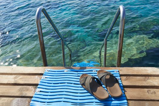 A pair of mens leather sandals by steps leading to sea