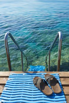A pair of mens leather sandals by steps leading to sea