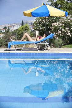 Young Woman Sunbathing In Bikini On Sunbed By Swimming Pool